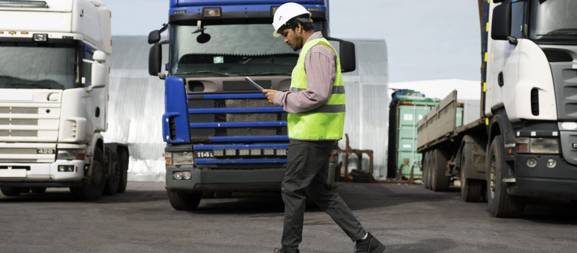 full-shot-man-walking-by-trucks-fleet